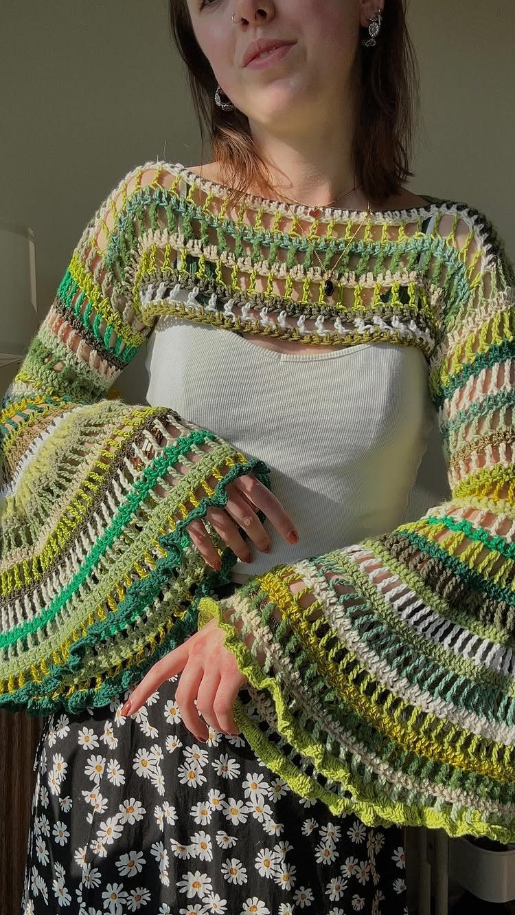 Woman wearing a colorful green and white crochet oversized shrug with wide bell sleeves.