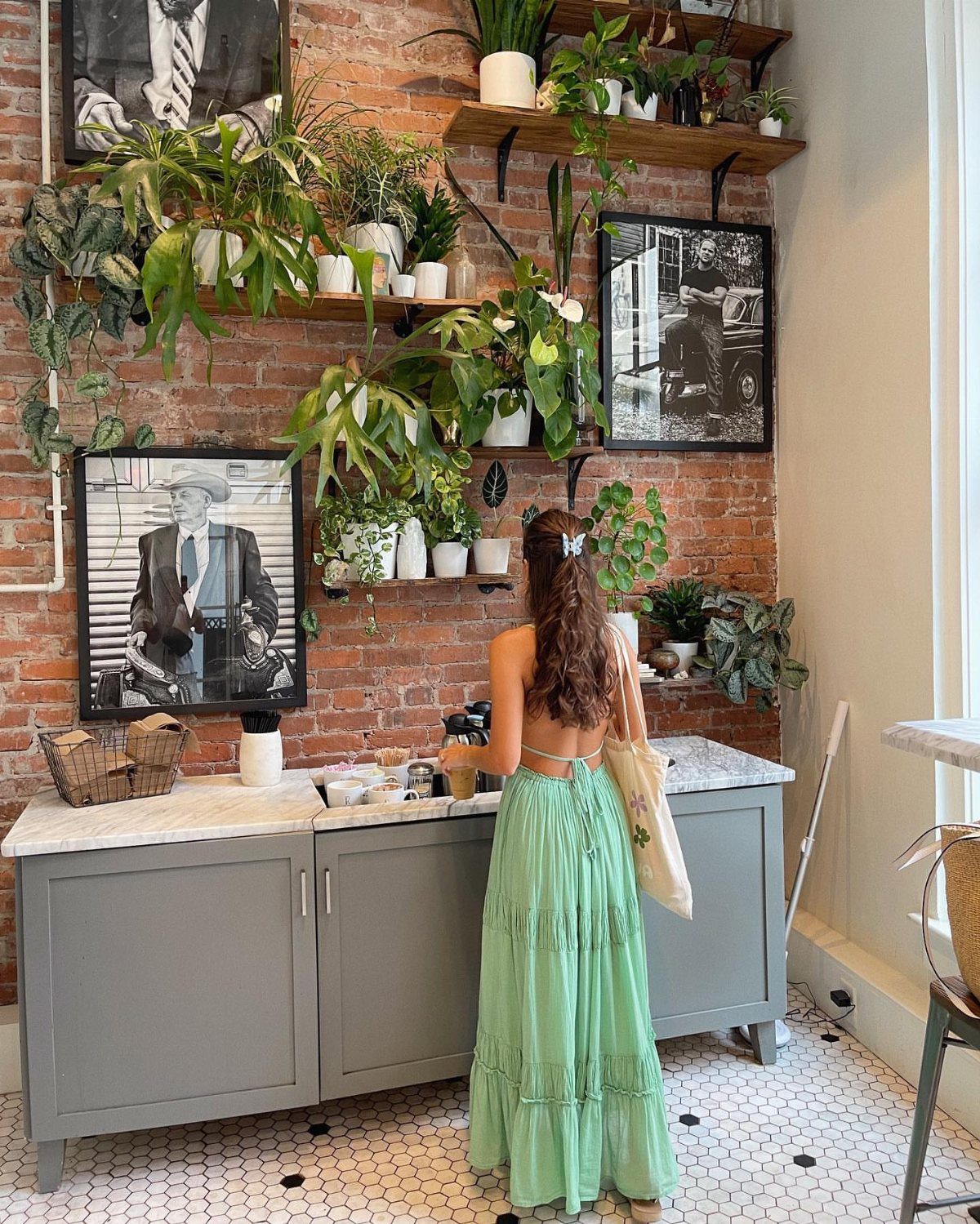 Woman in a long light green tiered maxi dress standing in a plant-filled room.