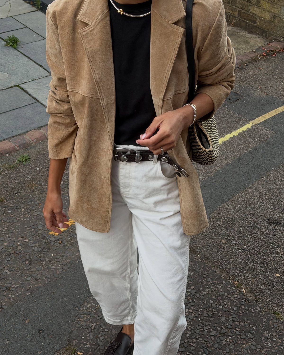 Person wearing a camel suede blazer, black shirt, and white jeans on a street.