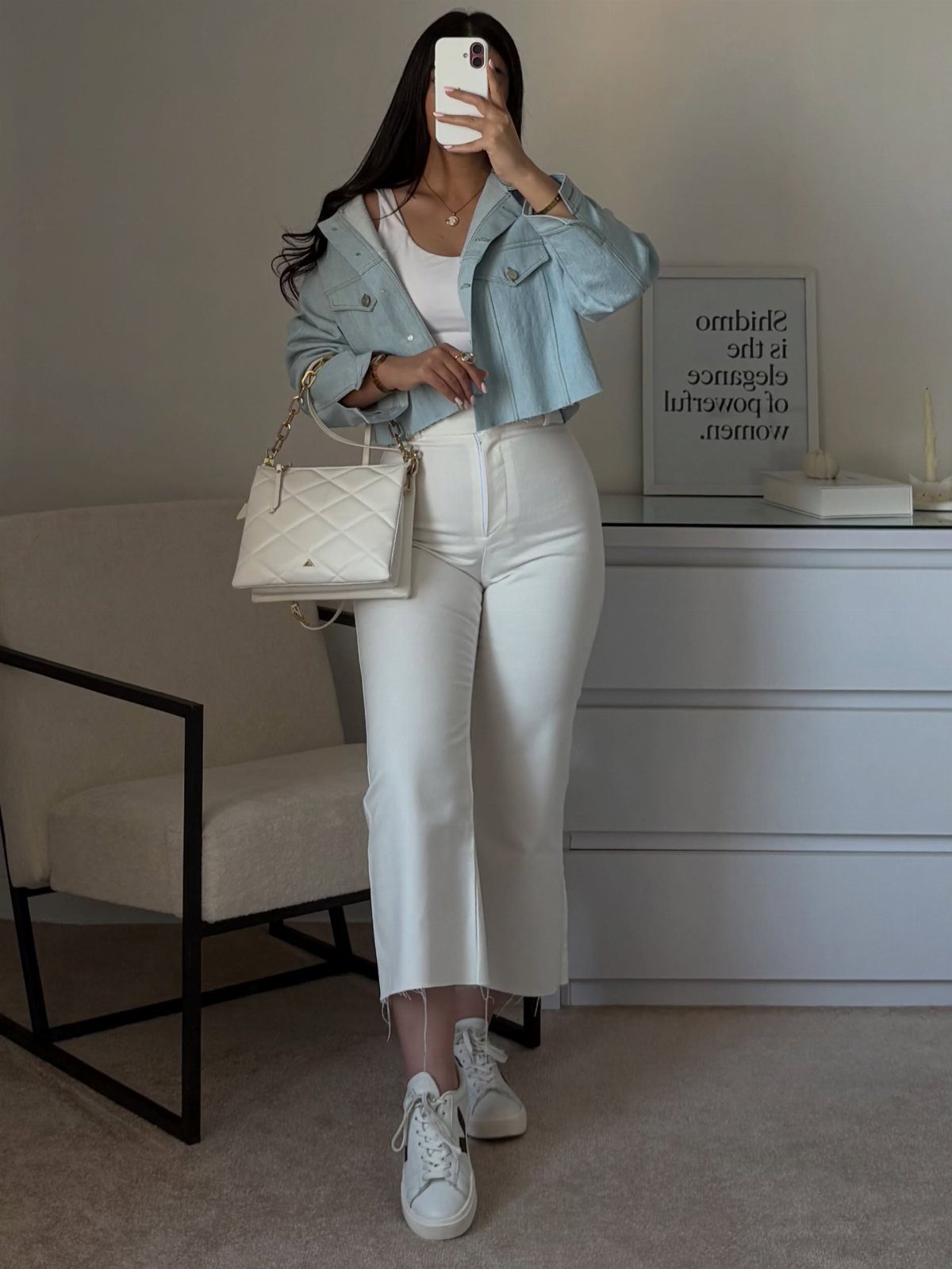 Woman wearing a light blue denim jacket with white jeans and white sneakers