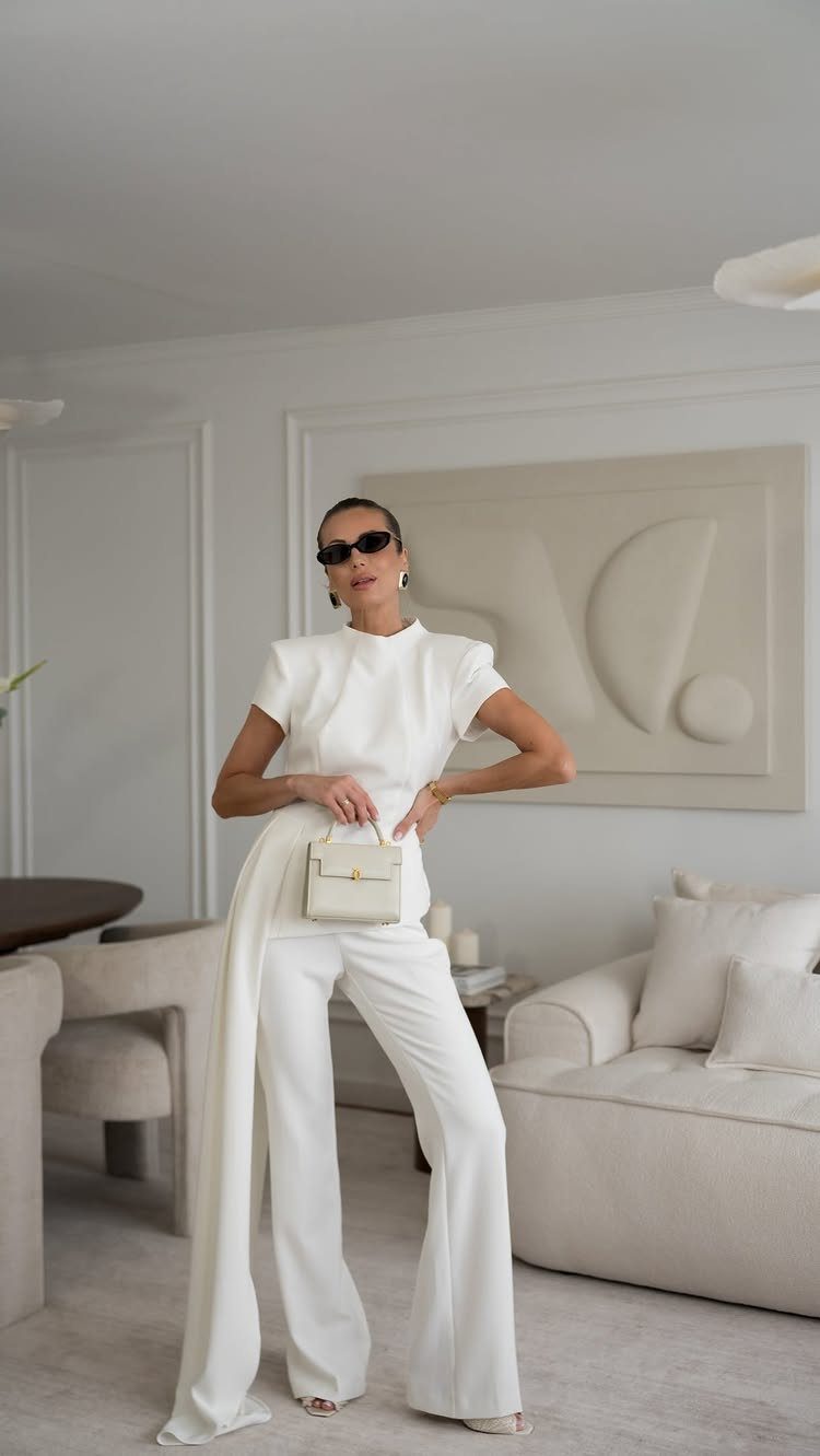 12 Wide Leg Pants Outfit Ideas, From Casual to Polished 2 Woman in a white short-sleeved top and white wide-leg trousers in a minimalist room.