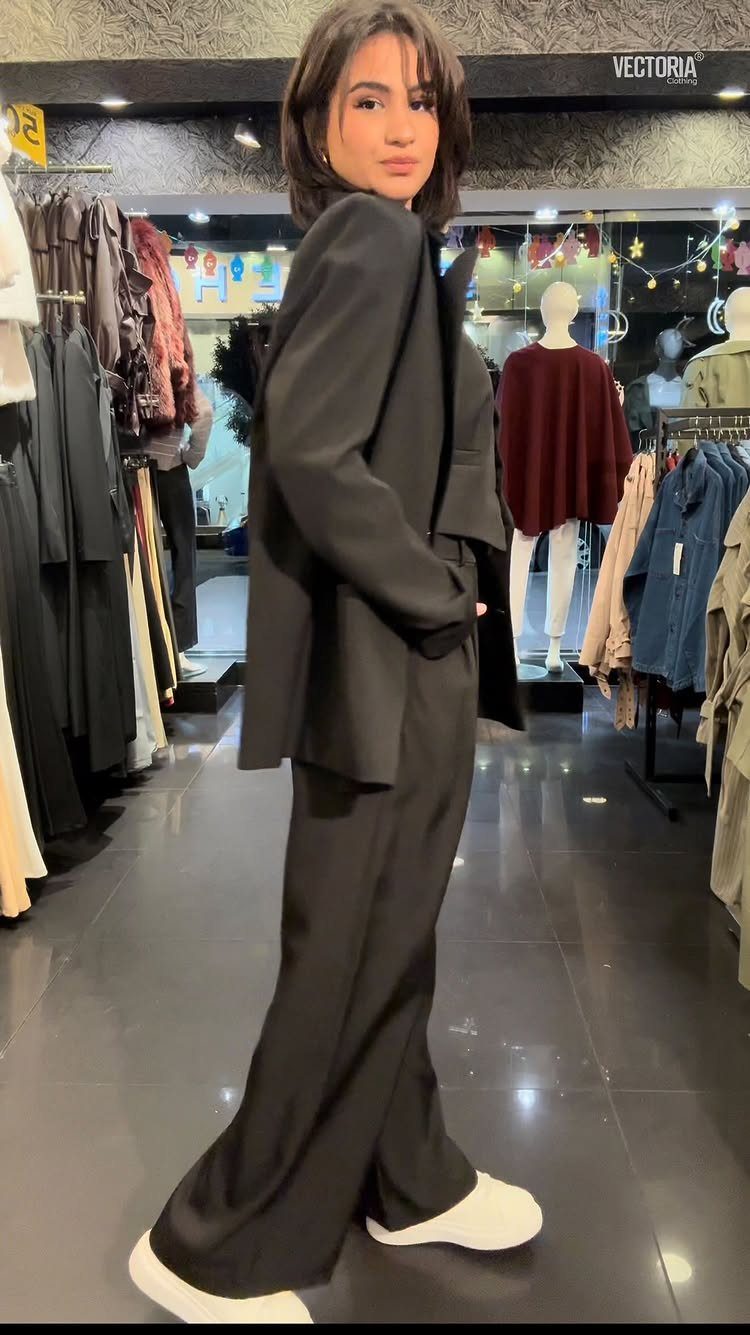 12 Wide Leg Pants Outfit Ideas, From Casual to Polished 4 Woman wearing a black oversized blazer and wide-leg trousers with white sneakers.