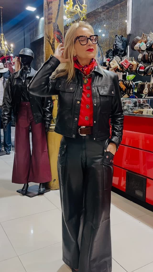 12 Wide Leg Pants Outfit Ideas, From Casual to Polished 6 Woman wearing a black leather jacket and wide-leg black leather trousers with a red scarf.