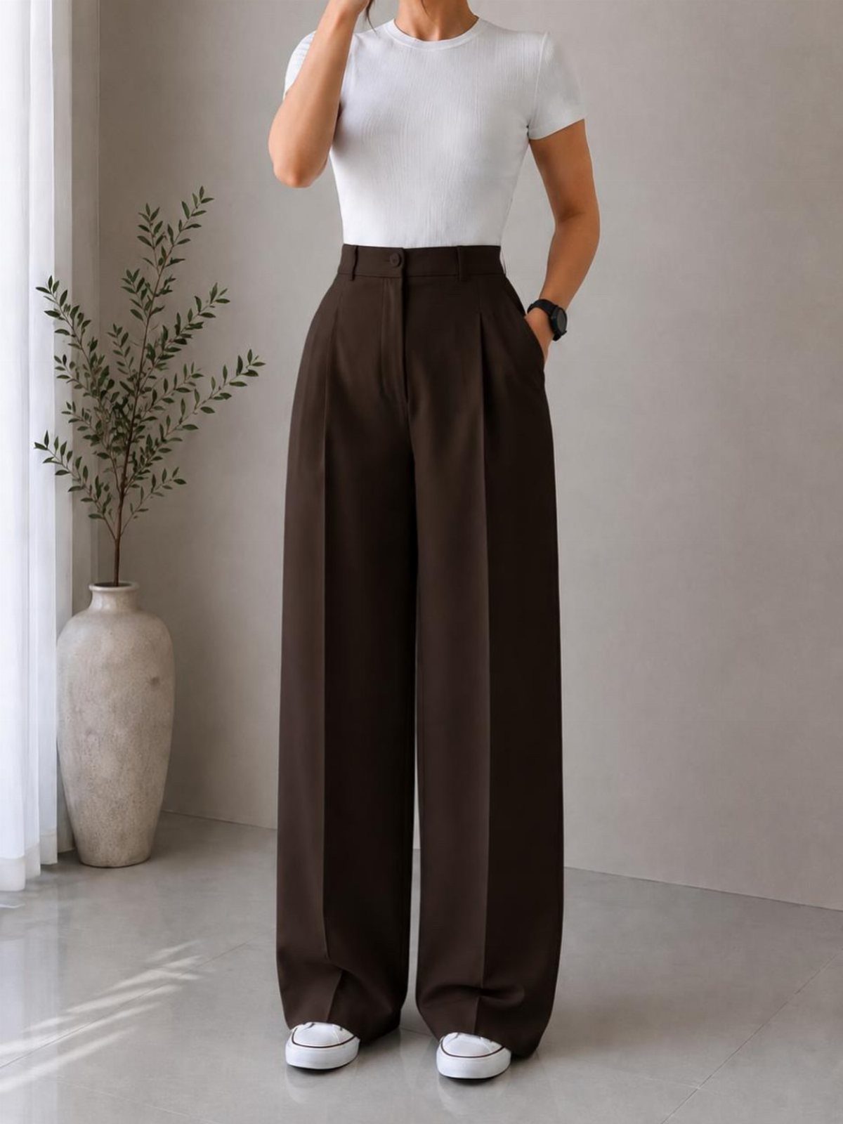 12 Wide Leg Pants Outfit Ideas, From Casual to Polished 1 Person wearing white t-shirt, brown wide-leg trousers, and white sneakers in a bright room.