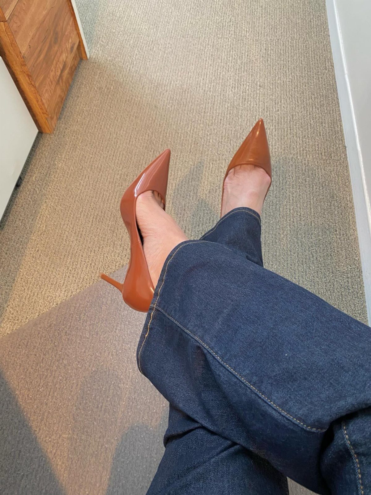 Women's Business Casual: 10 Outfit Ideas for the Office 6 Tan pointed-toe high-heeled pumps worn with dark blue denim jeans on a beige carpet.