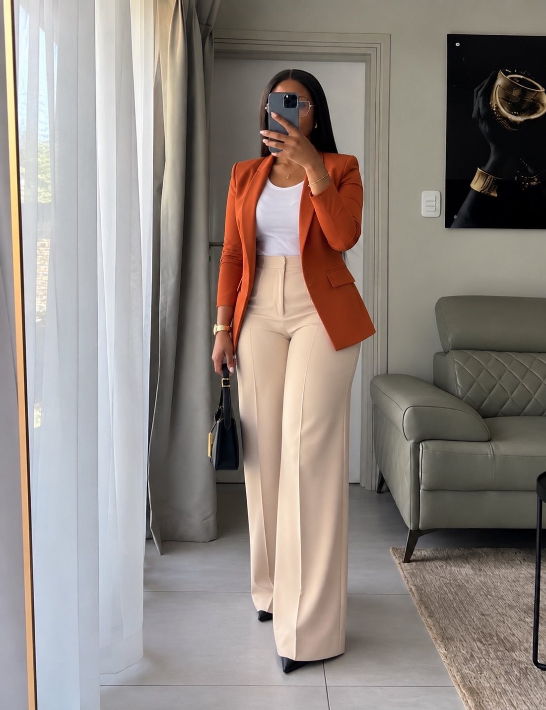 Women's Business Casual: 10 Outfit Ideas for the Office 4 Woman in an orange blazer and beige wide-leg dress pants posing for a mirror selfie.