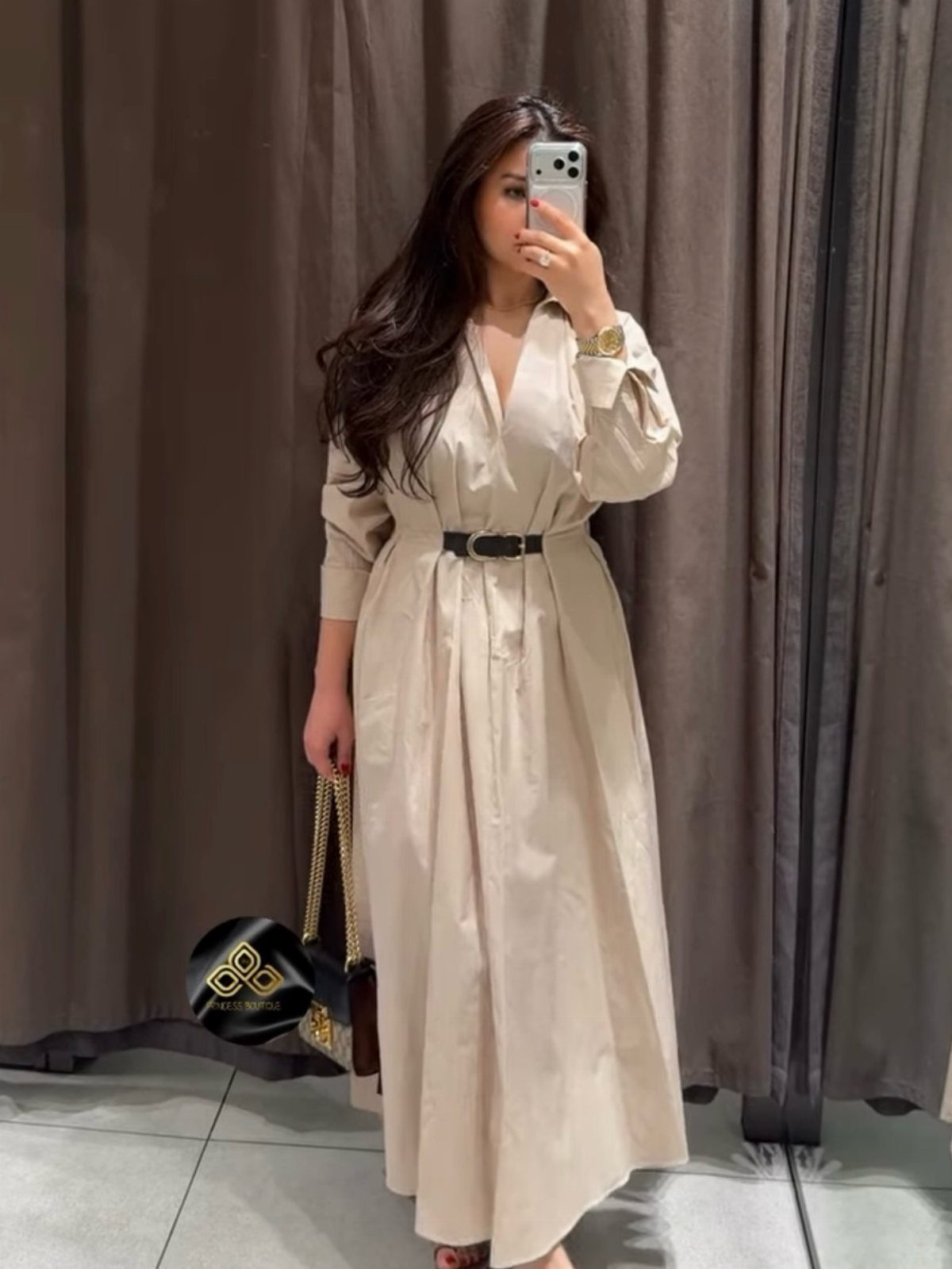 Women's Business Casual: 10 Outfit Ideas for the Office 5 A woman in a long beige A-line dress with a black belt posing for a mirror selfie.