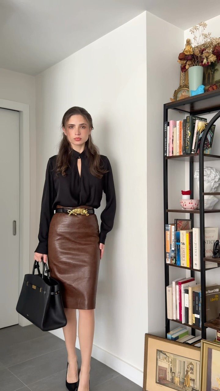 Women's Business Casual: 10 Outfit Ideas for the Office 3 Woman wearing a black blouse, brown leather pencil skirt, and black pumps holding a handbag.