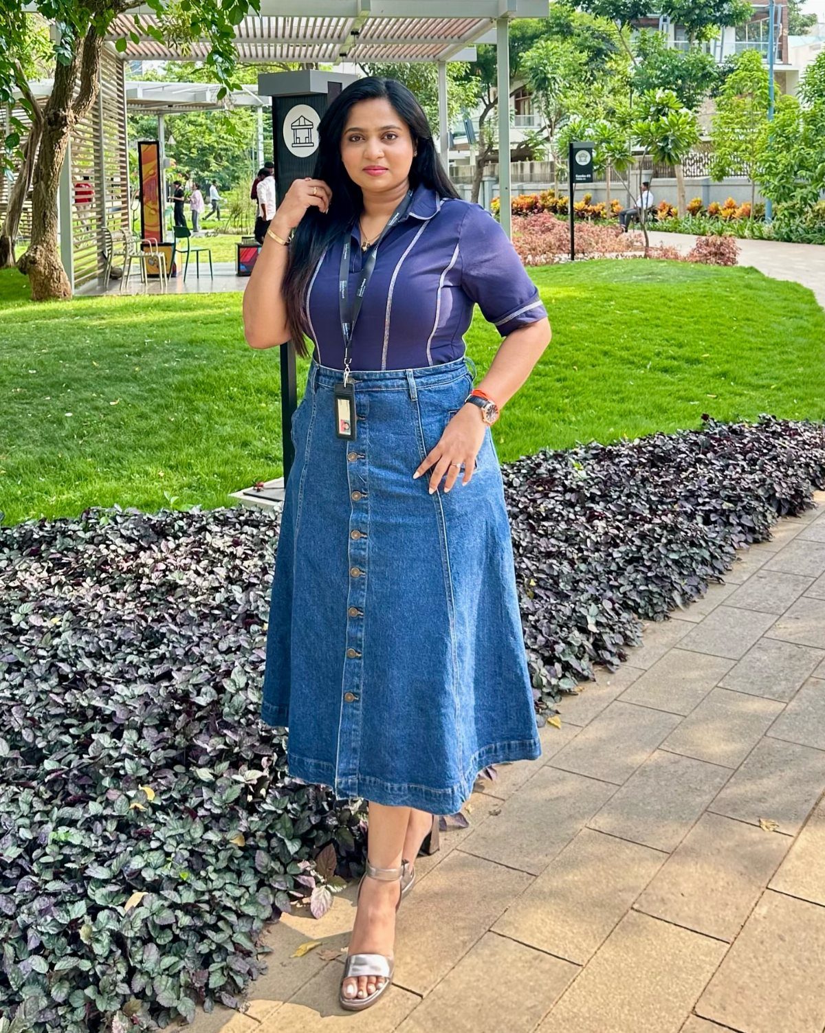 Woman wearing a blue button-down blouse and a long denim midi skirt outdoors.