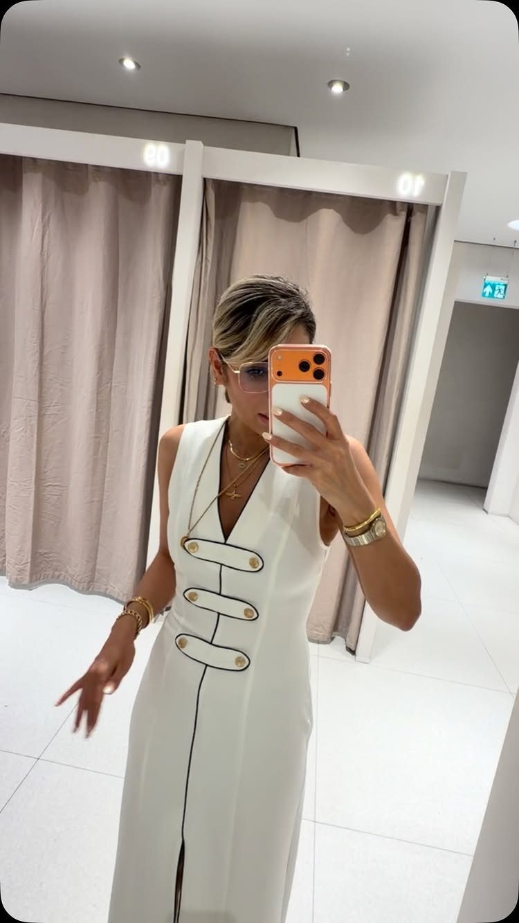 Zara Summer Dresses From Mini to Maxi (21 Characters) 14 Woman in a white sleeveless pencil dress with gold buttons in a fitting room