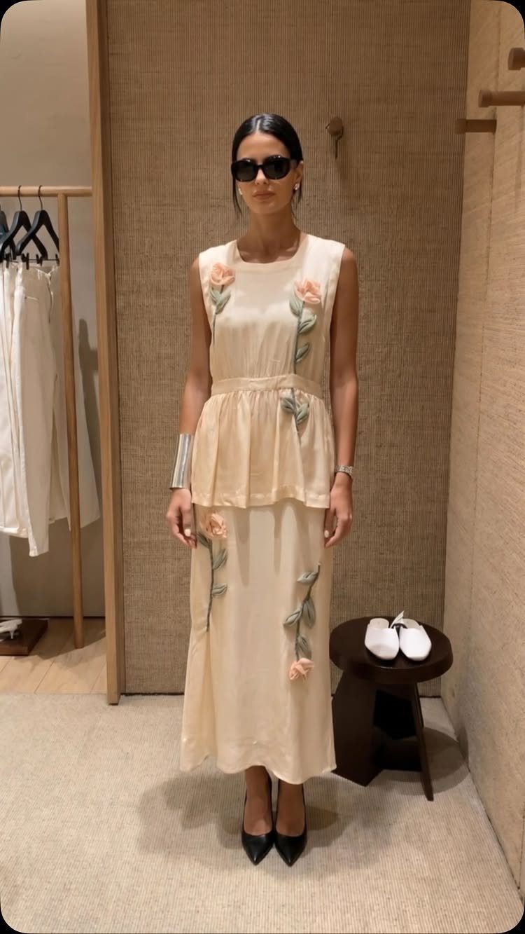 Zara Summer Dresses From Mini to Maxi (21 Characters) 21 Woman in cream sleeveless maxi dress with orange floral embroidery in a dressing room.