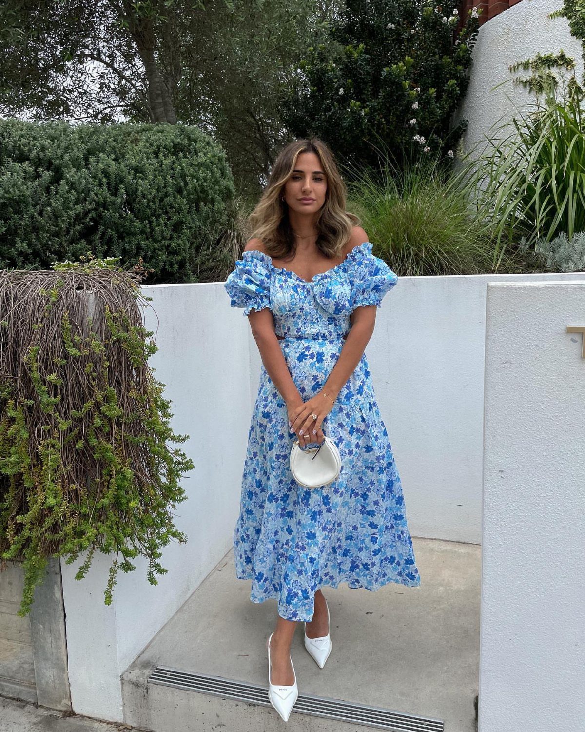 Zara Summer Dresses From Mini to Maxi (21 Characters) 3 Woman in a blue floral puff-sleeve midi dress with a sweetheart neckline and white heels.